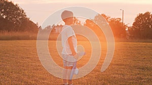 Boy plays with a toy plane in a field at sunset. The concept of childhood, freedom and inspiration.