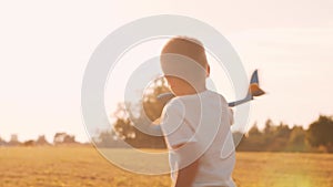 Boy plays with a toy plane in a field at sunset. The concept of childhood, freedom and inspiration.