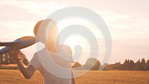 Boy plays with a toy plane in a field at sunset. The concept of childhood, freedom and inspiration.