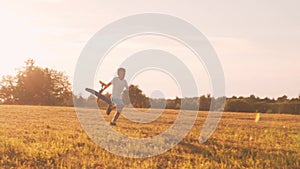 Boy plays with a toy plane in a field at sunset. The concept of childhood, freedom and inspiration.