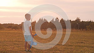 Boy plays with a toy plane in a field at sunset. The concept of childhood, freedom and inspiration.