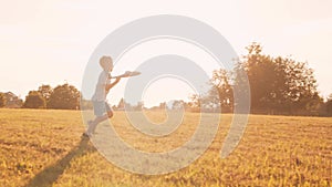 Boy plays with a toy plane in a field at sunset. The concept of childhood, freedom and inspiration.