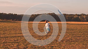 Boy plays with a toy plane in a field at sunset. The concept of childhood, freedom and inspiration.