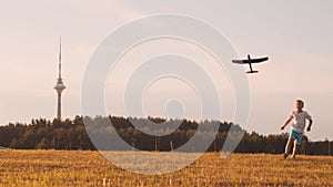 Boy plays with a toy plane in a field at sunset. The concept of childhood, freedom and inspiration.