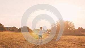 Boy plays with a toy plane in a field at sunset. The concept of childhood, freedom and inspiration.