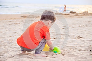 A boy plays a typewriter on the beach. Children`s games. Beach in the summer. Small child