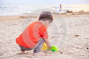 A boy plays a typewriter on the beach. Children`s games. Beach in the summer. Small child