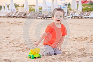 A boy plays a typewriter on the beach. Children`s games. Beach in the summer. Small child