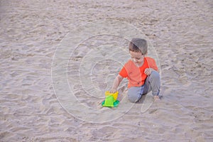 A boy plays a typewriter on the beach. Children`s games. Beach in the summer. Small child