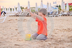 A boy plays a typewriter on the beach. Children`s games. Beach in the summer. Small child