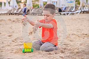 A boy plays a typewriter on the beach. Children`s games. Beach in the summer. Small child