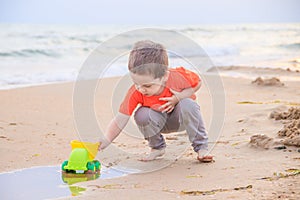 A boy plays a typewriter on the beach. Children`s games. Beach in the summer. Small child