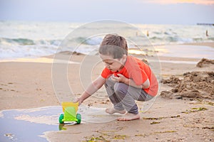 A boy plays a typewriter on the beach. Children`s games. Beach in the summer. Small child