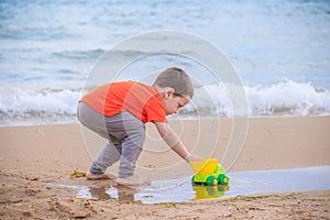 A boy plays a typewriter on the beach. Children`s games. Beach in the summer. Small child