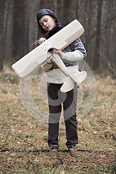 A boy plays in the woods with a toy plane. autumn games in the w