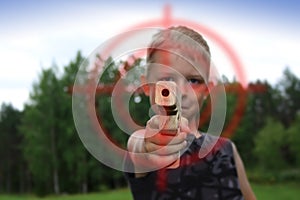 Boy pointing with wooden toy gun