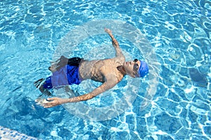 The Boy in the Pool is Resting After Training. A Sports Swimmer in Swimming Goggles is Preparing for a Swimming Lesson in the Pool