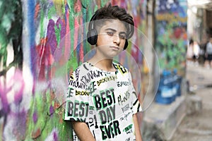 Boy portrait with earphones and grafiti behind photo