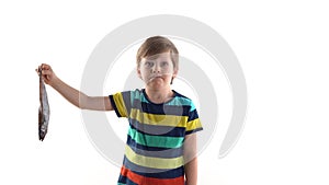 Boy posing in studio on a white background with raw fish, grimaces of disgust