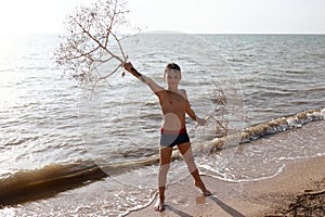 Boy posing with tumbleweed plant on beach of Azov sea