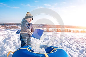 The boy pours snow child`s shovel. In the winter on the street in the city of the weekend. Rest with a child in nature