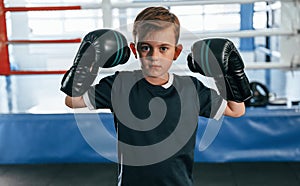 Boy is practicing boxing in the gym with glowes on hands