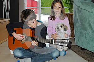 Boy practicing playing guitar, his sister sings