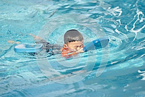 Boy practise swimming with foam pad floater in water