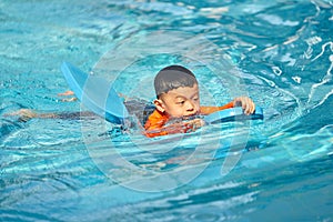 Boy practise swimming with foam pad floater in water