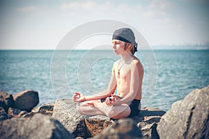 Boy practising yoga on beach
