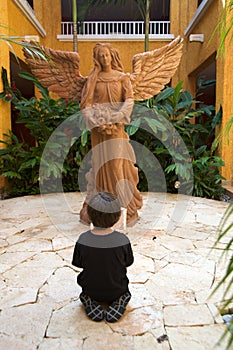 Boy praying in front of an angel