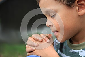 Boy praying to God with hands held together stock photo