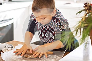 A boy prepares gingerbread cookies in the kitchen. Christmas family traditions. Leisure of the child during the New