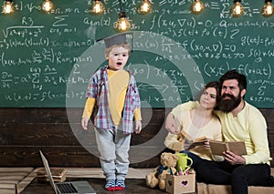 Boy presenting his knowledge to mom and dad. Smart child in graduate cap like to perform. Parents listening their son