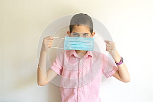 Boy with protection face mask against coronavirus in his hands.  Quarantine. Distance learning. Remote education.