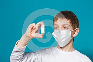 Boy in protection mask looking at pills