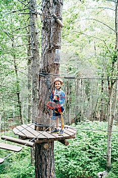 Boy in protective gear stands on a wooden platform in front of the agility bridge