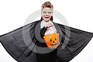 Boy with pumpkin basket dressed like vampire for Halloween party