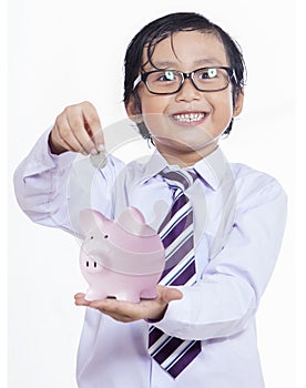 Boy puts the coin into a piggy bank