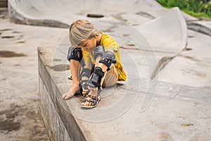 Boy puts on knee pads and armbands before training skate board