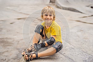 Boy puts on knee pads and armbands before training skate board