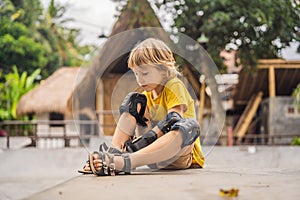 Boy puts on knee pads and armbands before training skate board