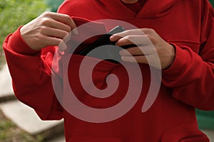 Boy putting mobile phone in pocket of hoodie