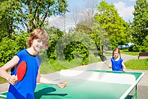 Boy with racket serves table tennis ball to girl