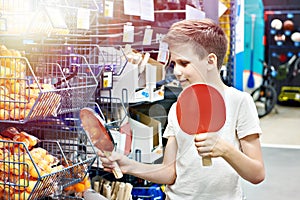 Boy with rackets for table tennis in sport store