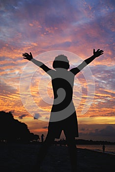 Boy raise arms to sunset