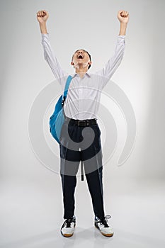 a boy raises his hand in a junior high school uniform in high spirits with a school bag