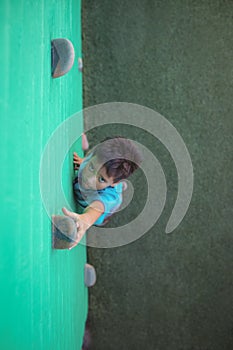 Boy reaching climbing holds on green wall