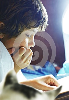 Boy read book in bed with cat