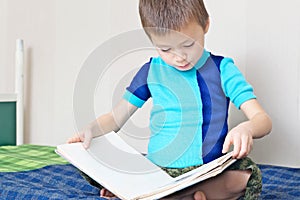 Boy reading book on bed